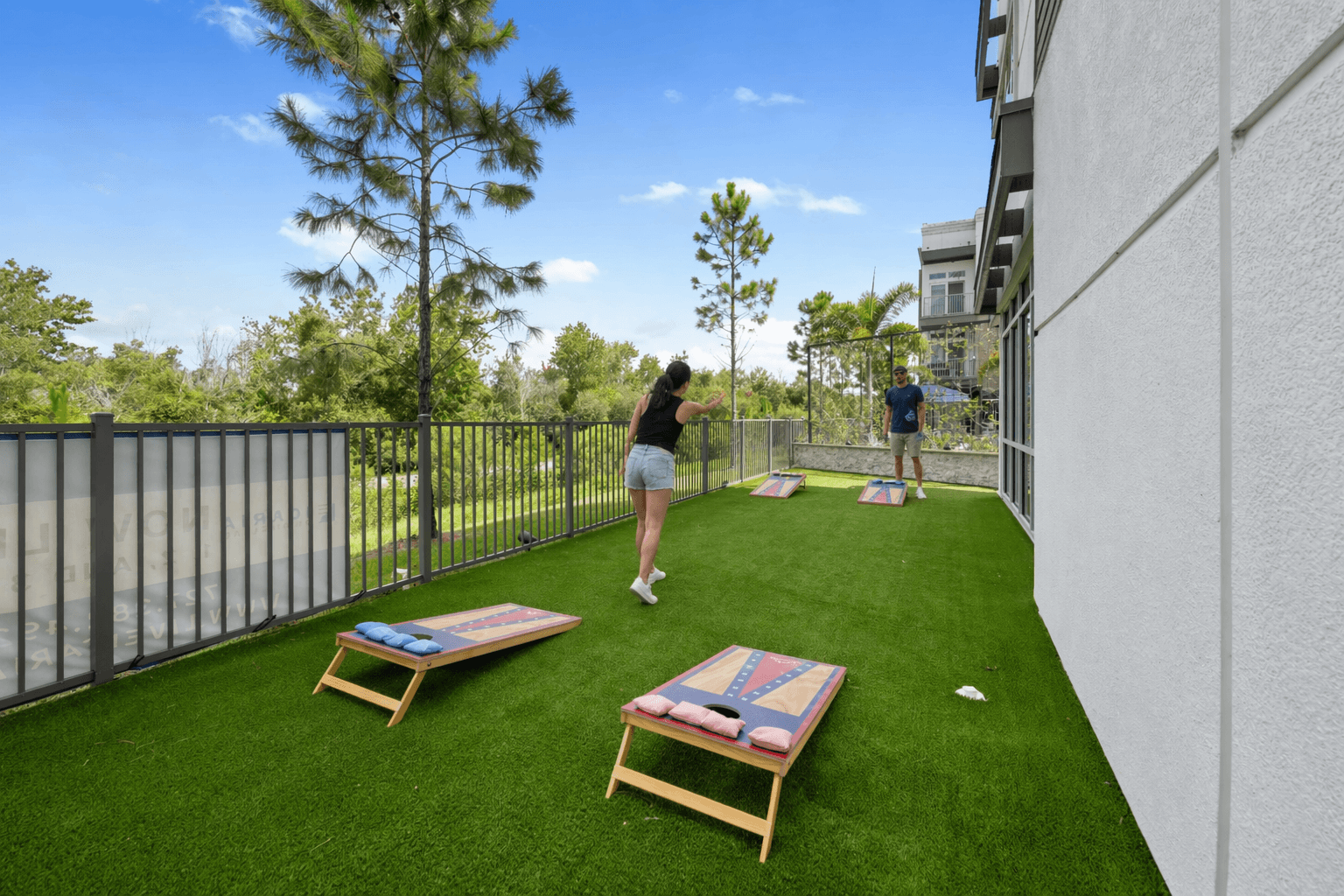 A woman is standing on a small lawn with a man in the background.